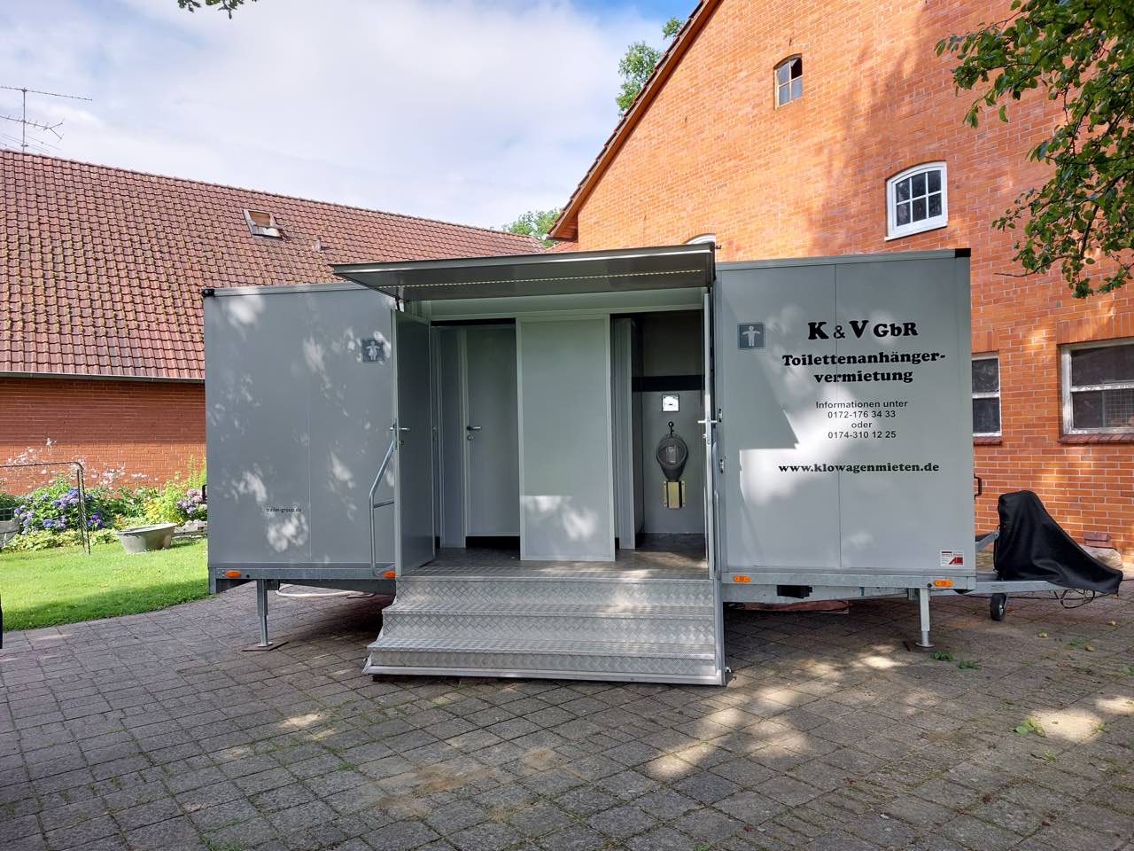 Toilettenanhänger vor einem Fachwerkhaus mit Klinkerfassade